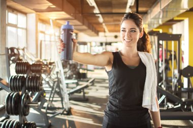 Spor salonunda elinde su şişesi olan sportif bir kadın.