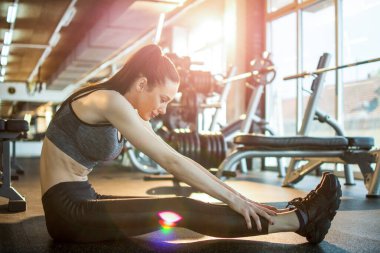 Spor salonunda esneme hareketleri giyen zayıf, güzel bir kadının yan görüntüsü..
