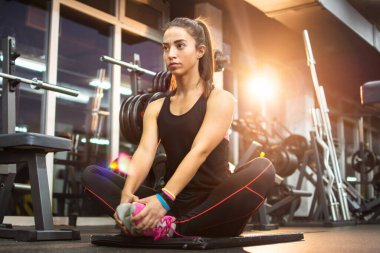 Sportif kız spor salonunda egzersiz paspası üzerinde dinlendirici egzersizler yapıyor..