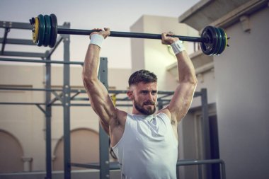 Kas yığını genç adam halterleri kaldırıyor..