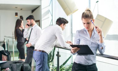 Endişeli sarışın iş kadını ofis koridorunda belgeye bakıyor.