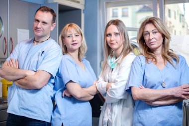 Bir grup dişçi dişçi, dişçi ofisinde kameraya bakıyor.