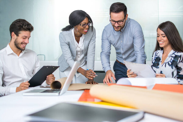 Группа молодых перспективных архитекторов просматривает проектные документы в офисе.