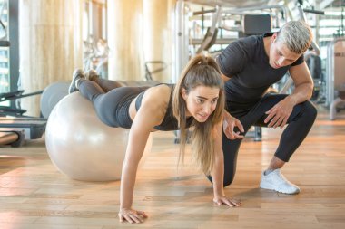 Spor salonundaki spor salonundaki sporcu kadını denetleyen antrenör..