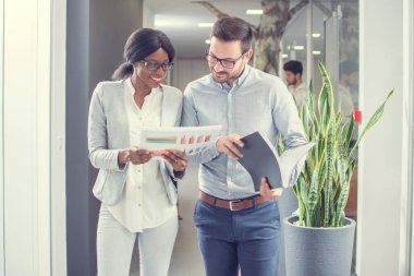 Ofis koridorunda gayri resmi görüşme yaparken iki işadamı belgelerle birlikte çalışıyor..