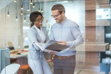 Modern ofiste çalışan neşeli iş adamlarının cam manzarası sayesinde..