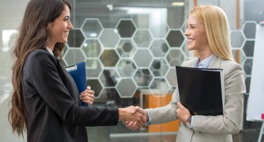 Güzel genç iş kadınları başarılı bir buluşmadan sonra el sıkışıyor.