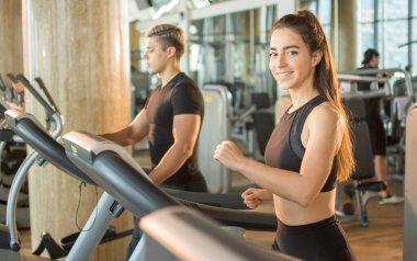 Spor salonunda koşu bandında koşan çekici genç bir kadın..