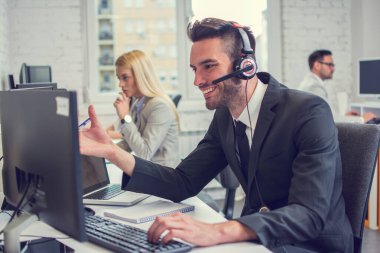 Ofiste bilgisayarla çalışan yakışıklı bir iş adamı.