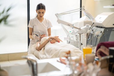 Güzellik uzmanı modern güzellik salonunda cilt bakımı için radyo frekansı güzellik makinesi kullanıyor..