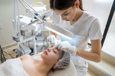 Güzellik uzmanının güzellik salonundaki kozmetik prosedürü sırasında kadın müşterilerin yüzlerindeki siyah noktaları sıkması ve çıkarması.