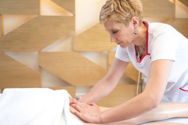 Kadın terapist güzellik salonundaki müşteriye rahatlatıcı ayak masajı yapıyor.