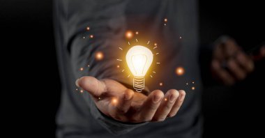 Ampulü tutan el. Yenilikçi ve ilham verici bir fikir. Elinde ampul ışığı çizimi fikri