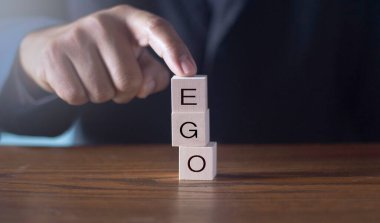 Tahta alfabe blokları - Ego - kavramsal bir resimde avucunun içinde dengelenmiş.