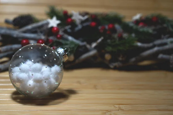 Christmas tree toy with fluffy balls inside, with dicorations on the back on wooden table