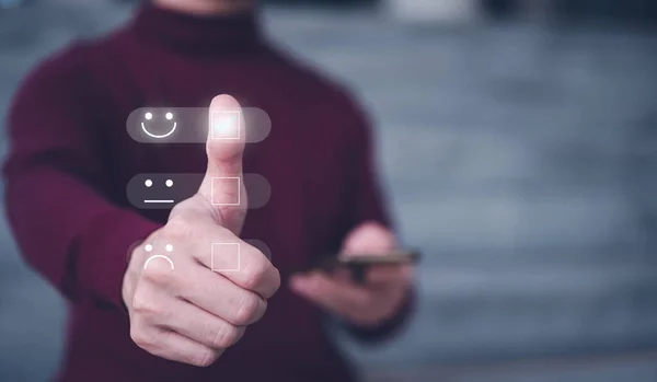 Customer service satisfaction survey concept.Business people or customers show satisfaction by thumb up on face emoticon smile in satisfaction on virtual touch screen