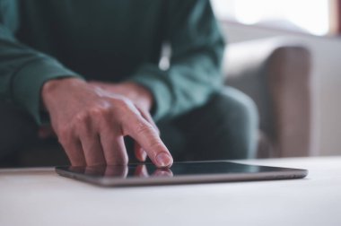 İş adamı kanepede oturup mol tablet kullanarak internet ağı platformunda geziniyor, iş analizi ve strateji yapıyor.