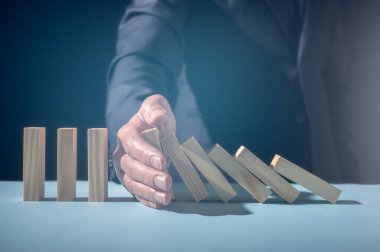 İşadamı eli çökmeyi durdurdu tahta blok dominosu. Risk ve Strateji, risk yönetimi konsepti, iş adamının tahta blokların çökmesini durdurması veya domino etkisi düşmesi