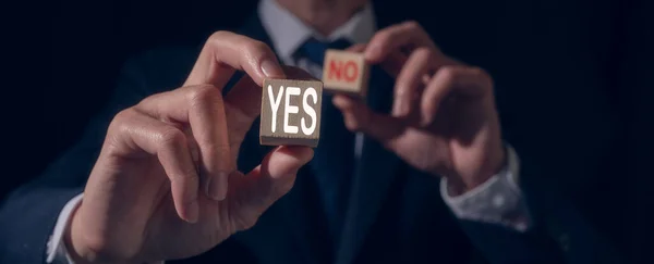 the concept of making a decision Yes or No. Businessman hand is making a choice between YES and No symbol on wooden block. customer survey feedback and satisfaction