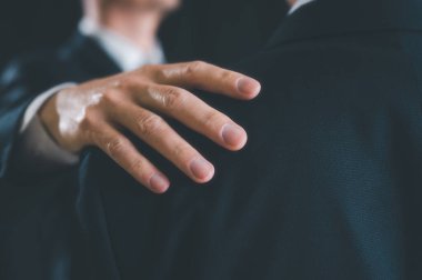 İş adamı elini arkadaşının omzuna koydu. Cesaret, sevgi, destek konsepti verdi. Sevgililer Günü konsepti, herkese sevgi vermek. Akıl sağlığı, aşk ve hayat sorunları hakkında danışmanlık yapan bir arkadaş.