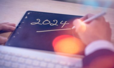 2024 takvimi ile çalışan dijital tablet veya akıllı telefon kullanan 2024 erkek için mali planlama ve anımsatma kavramı, iş planlaması ve yatırım
