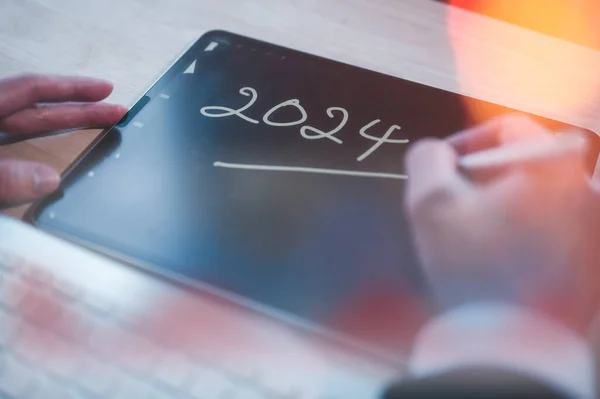 Concept for financial planning and reminder for 2024. man using digital tablet or smartphone working with calendar 2024, business planning marketing and investment