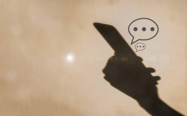 Duvarda akıllı telefon ve Speec baloncuğunun gölgesi bulanık arka plan, sosyal medya çevrimiçi yaşam tarzı teknolojisi