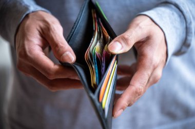 Elinde para ve kartlarla cüzdan tutan ve açan bir adam.