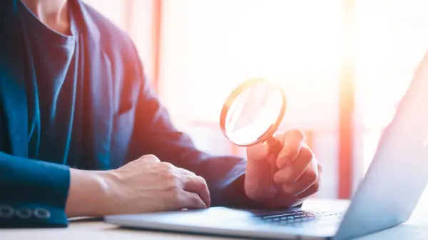 Searching opportunity businessman looking through a magnifying glass to documents. Business assessment and audit. Magnifying glass on a financial report