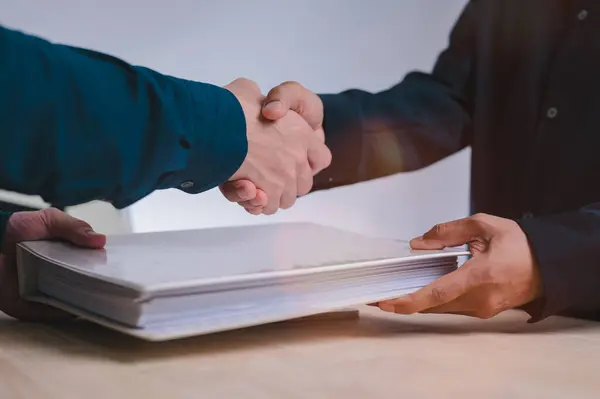 Hand shake concept, businessman is shaking their hands together and holding document folder for greeting dealing business join venture or investment in successful business