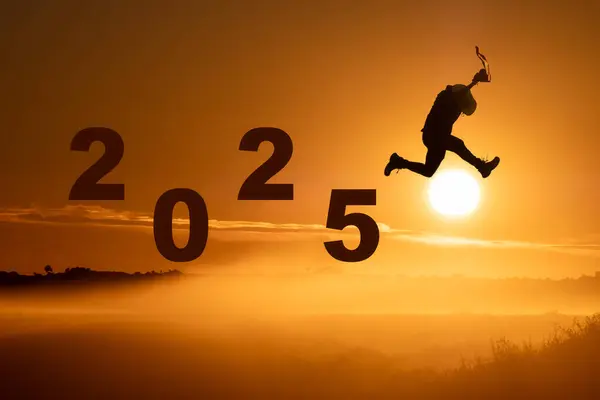 a man jump happy new year 2025 concept, silhouette of a man jumping over the sun in sunrise background, startup business and life style concept