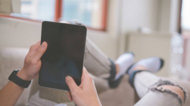 Sosyal medya eğlencesi ve yaşam tarzı konsepti. Oturma odasında elinde dijital tablet olan bir adam.