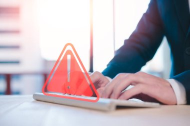 İnternet ağındaki risk ve siber güvenlik. İş adamı, uyarı üçgeni uyarı işaretli bilgisayar klavyesi kullanıyor. Uyarı hatası ve bakım kavramı için.