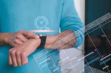 Zaman yönetimi iş planlama konsepti. İş adamı bulanık saat arkaplan kullanan akıllı saat kullanıyor.