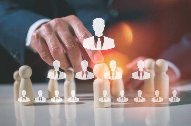 İşadamı lideri bir grup çalışandan tahta insanları seçiyor, İşletme & İK küresel tahta bulmaca konsepti liderlik ve takım için mandallı bebek ve işadamı eli