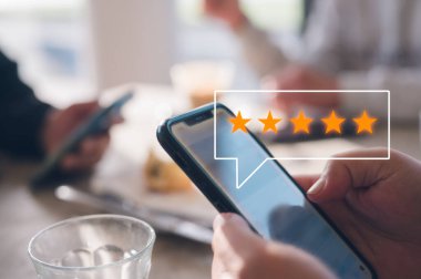Müşteri hizmetleri deneyimi ve memnuniyet araştırması konsepti insan müşterisinin akıllı telefondan beş yıldızlı not vermesine yakın çekim. İnceleme, Hizmet derecesi, memnuniyet