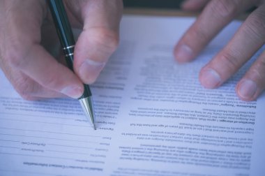 İş adamı yasal bir belge imzalıyor, idari müdür elle kağıt işi belgesi dolduruyor, sözleşme imzalıyor, ortaklık anlaşması imzalıyor, kapatılıyor.