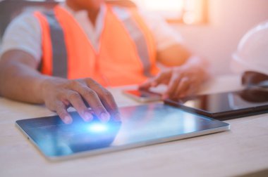 Ofiste çalışan bir mühendis dijital tablet kullanarak masada oturuyor.