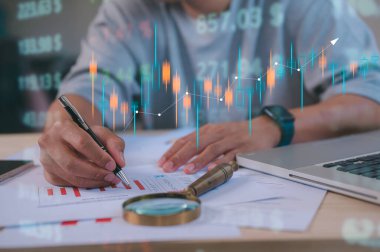 Yatırım finansal konsept veri analizi grafiği. Finansal yönetim teknolojisi. Sanal ekranda KPI Kontrol Paneli kullanılıyor, adam veri grafikleriyle çalışan kalem büyüteç ve bilgisayar dizüstü bilgisayar kullanıyor