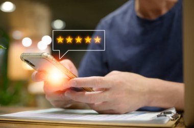Müşteri hizmetleri deneyimi ve memnuniyet anketi konsepti. Kafede ya da restoranda oturan müşterinin akıllı telefondan beş yıldızlı bir not vermesi. İnceleme, Hizmet derecesi, memnuniyet