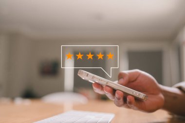 Müşteri hizmetleri deneyimi ve memnuniyet anketi konsepti. Kafede ya da restoranda oturan müşterinin akıllı telefondan beş yıldızlı bir not vermesi. İnceleme, Hizmet derecesi, memnuniyet