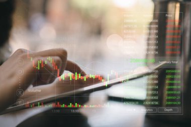 Kafede oturan kadın, izleme odasındaki veri borsasını analiz etmek için tablet kullanıyor. Ekip, tablodaki verileri işaret ediyor. Mali yatırım kavramı.