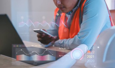 Otomasyon için fütüristik çizelge arayüzüne sahip akıllı telefon ve bilgisayar kullanan ve gelecekçi endüstriyel otomasyonu izleyen, akıllı fabrika teknolojisi, yenilik kavramını izleyen bir mühendis.