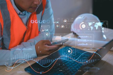 Otomasyon için fütüristik çizelge arayüzüne sahip akıllı telefon ve bilgisayar kullanan ve gelecekçi endüstriyel otomasyonu izleyen, akıllı fabrika teknolojisi, yenilik kavramını izleyen bir mühendis.