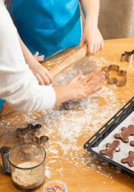Anne ve kızın hamuru yuvarlarken ve mutfakta kurabiye keskisi kullanırken en iyi görüntü. Un, yemek tepsisi, ev yapımı kurabiyeler. Kavram: Aile, bağ, yaratıcılık