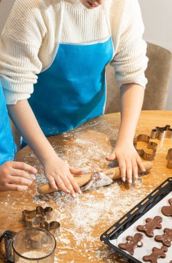 Anne ve kızın hamuru yuvarlarken ve mutfakta kurabiye keskisi kullanırken en iyi görüntü. Un, yemek tepsisi, ev yapımı kurabiyeler. Kavram: Aile, bağ, yaratıcılık