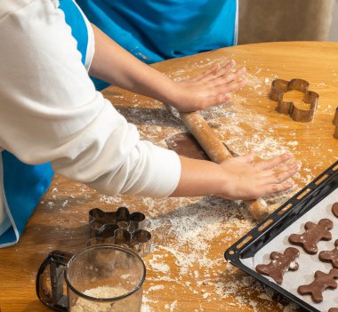 Anne ve kızın hamuru yuvarlarken ve mutfakta kurabiye keskisi kullanırken en iyi görüntü. Un, yemek tepsisi, ev yapımı kurabiyeler. Kavram: Aile, bağ, yaratıcılık