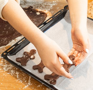 Çocuklar, ebeveynler ve çocuklar evde kurabiye pişiriyorlar. Un kaplı masada kurabiye keskisi kullanarak çikolata hamuru yuvarlamak. Ev yapımı pastalar ve tatil aile aktiviteleri.