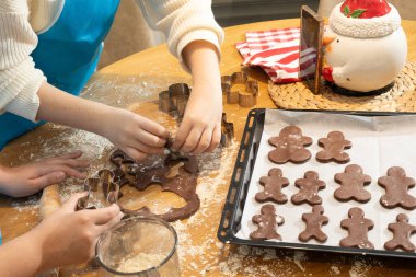 Anne ve kızın hamuru yuvarlarken ve mutfakta kurabiye keskisi kullanırken en iyi görüntü. Un, yemek tepsisi, ev yapımı kurabiyeler. Kavram: Aile, bağ, yaratıcılık