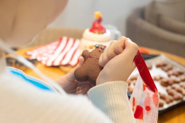 Çocuklar, ebeveynler ve çocuklar evde kurabiye pişiriyorlar. Un kaplı masada kurabiye keskisi kullanarak çikolata hamuru yuvarlamak. Ev yapımı pastalar ve tatil aile aktiviteleri.